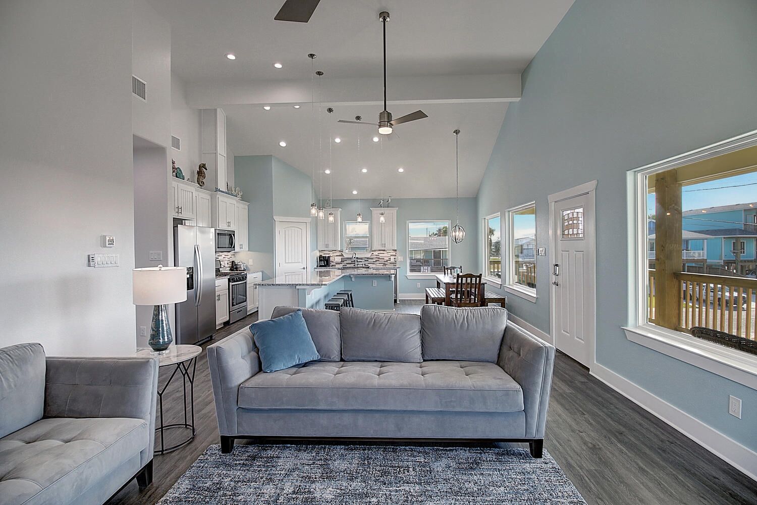 A modern kitchen with white cabinets, a central island, and a dining area with a table and chairs.