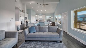 Une cuisine moderne avec des meubles blancs, un îlot central et un coin repas comprenant une table et des chaises.
