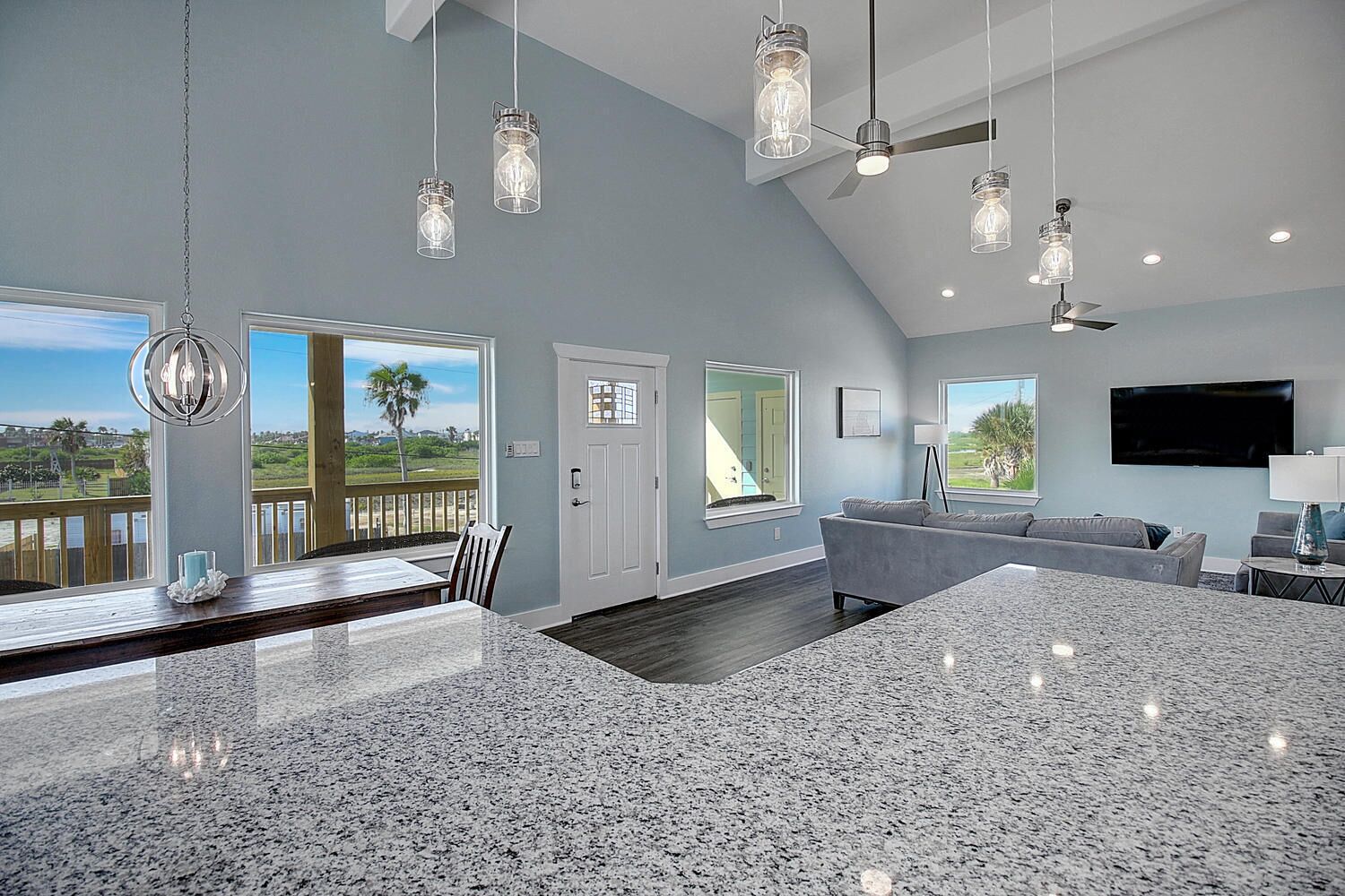 A spacious living area with a large kitchen island, a dining area with a view, and a balcony with a view.