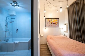 Un bagno moderno con doccia, un letto e un quadro appeso al muro.