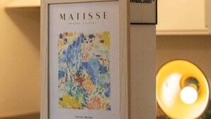 Eine Wand mit gerahmten Kunstwerken und motivierenden Sprüchen.