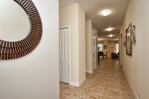 Un couloir orné d’une décoration murale circulaire, avec des portes blanches et un coin repas à l’arrière-plan.