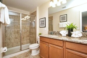 Une salle de bain avec une douche à parois de verre, des toilettes, un meuble-lavabo et un miroir.