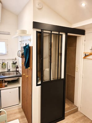 Cocina compacta con pileta, un refrigerador pequeño y un panel de pared de madera.
