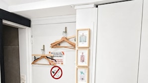Uma porta branca com placa de proibido fumar, cabides de madeira e quadros na parede.