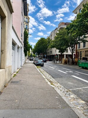 Une rue de la ville, avec des immeubles, des voitures garées et un trottoir.