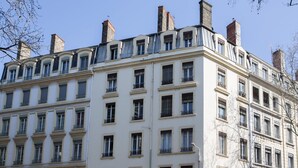 A multi-story building with a classic architectural style, featuring symmetrical windows and balconies. - Beautiful atypical apartment AC / garage (Lyon)