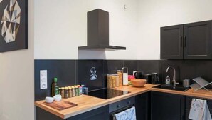 A modern kitchen with black cabinets, a wooden countertop, a built-in stove, and a black range hood.