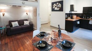 A compact living space with a bunk bed, a dining area with a round table, and a kitchenette.