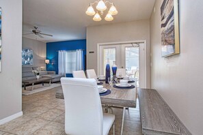 A dining area with a table set for four, a ceiling fan, and a view of the outside through a door. - Paradise Palms-4 Bed Townhome W/spashpool-3015pp 4 Bedroom Townhouse by RedAwning (Kissimmee)