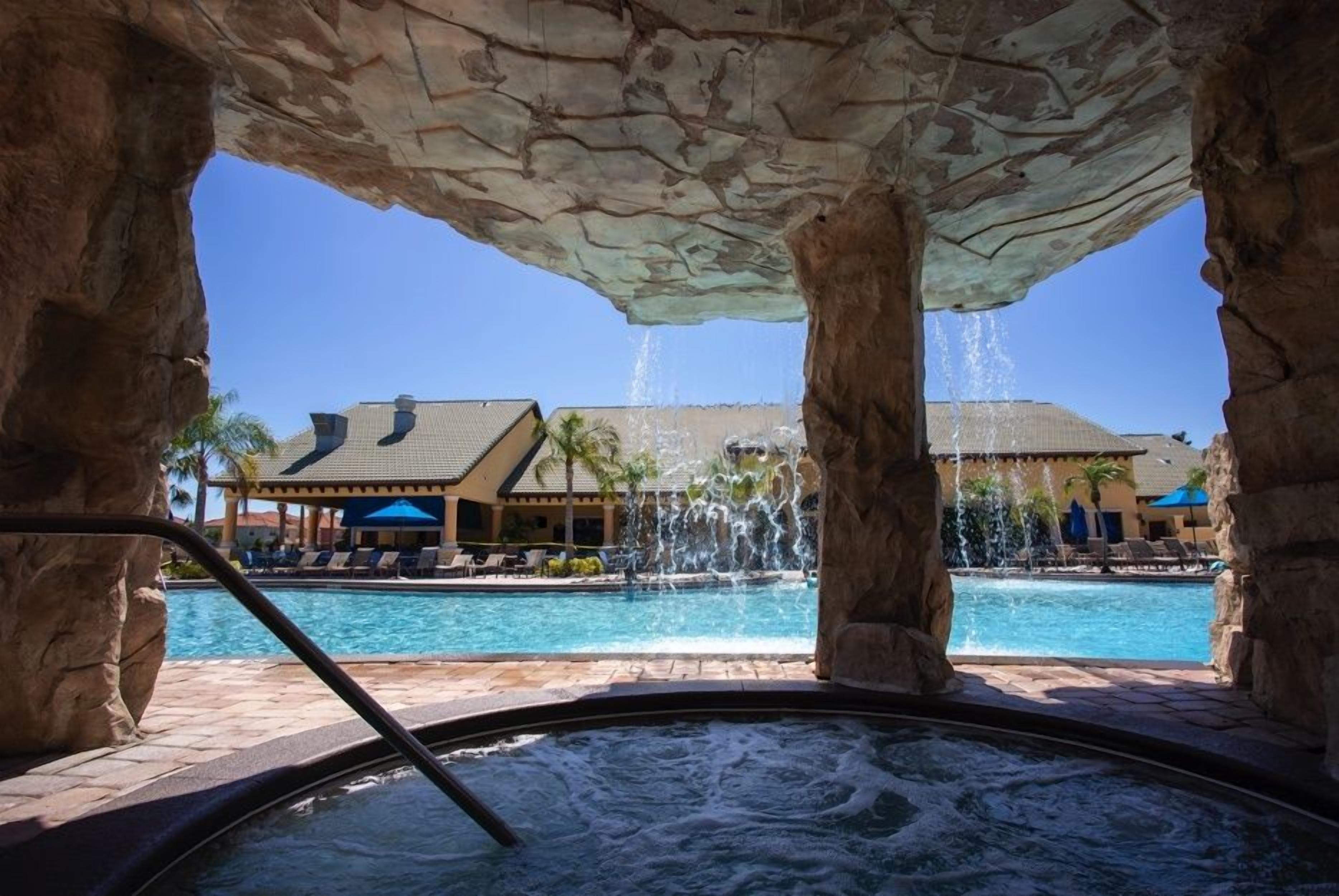 Un jacuzzi con vistas a una piscina y un edificio con tejado de azulejos.