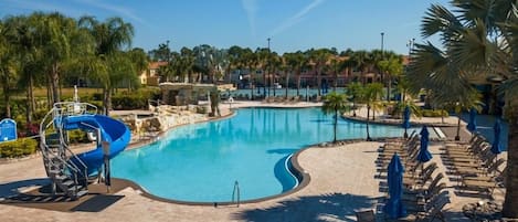 Une piscine avec un toboggan, des chaises longues et des parasols.