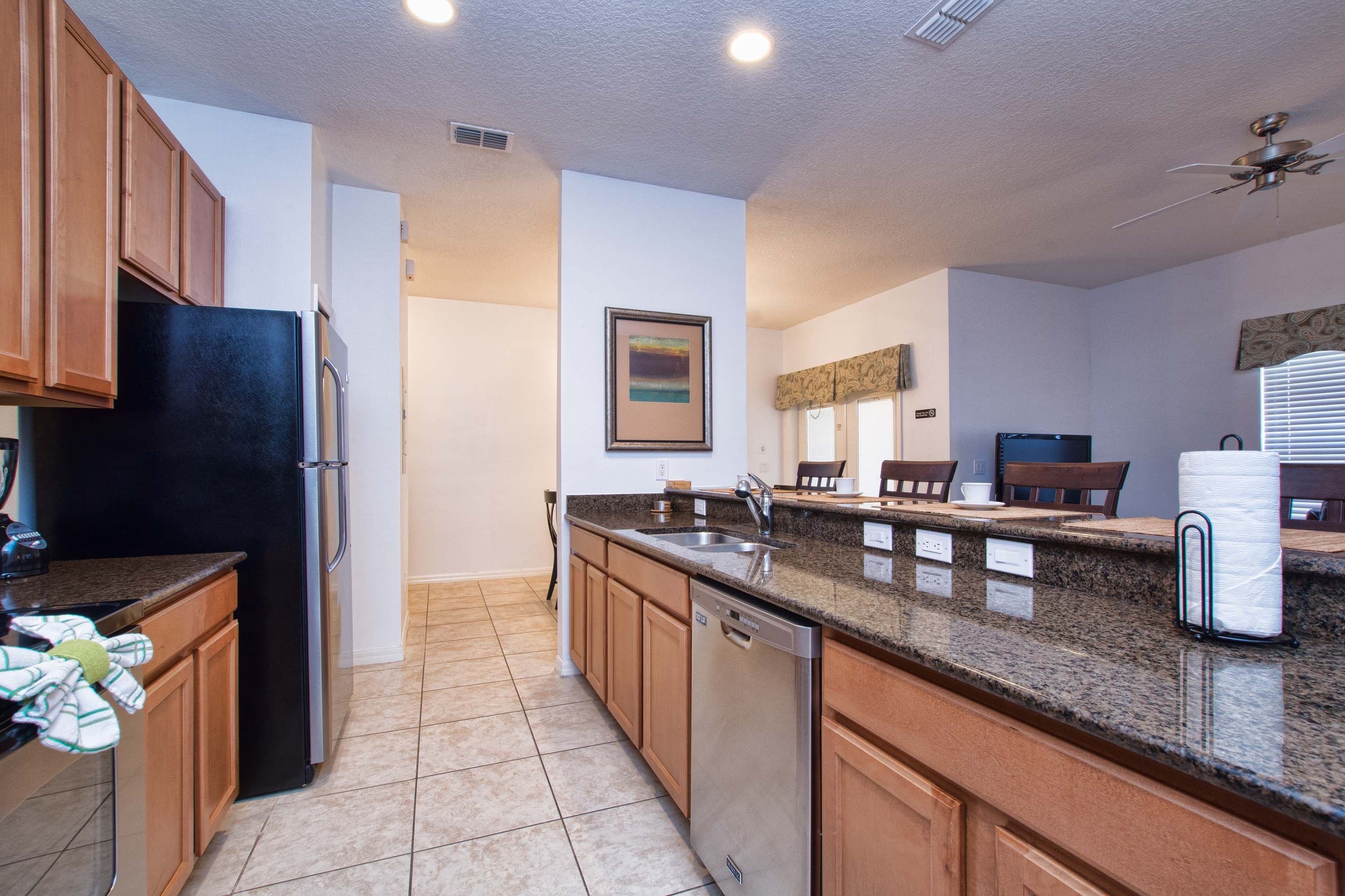 A modern kitchen with granite countertops, wooden cabinets, and a dishwasher.