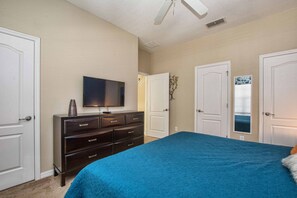 Une chambre à coucher comprenant un lit, une commode, un téléviseur et deux portes.
