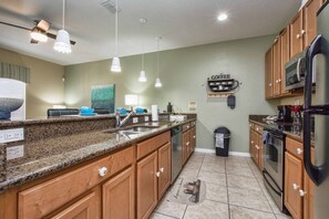 A kitchen with granite countertops, wooden cabinets, a stainless steel refrigerator, and a coffee station. - Paradise Palms- 4 Bed Townhome W/splashpool-3057pp 4 Bedroom Townhouse by RedAwning (Kissimmee)