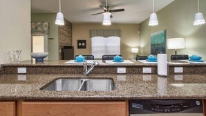 A kitchen with granite countertops, a stainless steel sink, a ceiling fan, and pendant lights. - Paradise Palms- 4 Bed Townhome W/splashpool-3057pp 4 Bedroom Townhouse by RedAwning (Kissimmee)