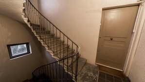 A spiral staircase with a metal railing, a small window, and a door with a handle.