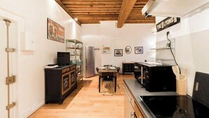 A compact kitchen with wooden flooring, a dining table, and a black stove.