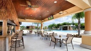 An outdoor seating area with tables and chairs, a pool, and a ceiling fan. - Paradise Palms- 4 Bed Townhome W/splashpool-3202pp 4 Bedroom Townhouse by RedAwning (Kissimmee)