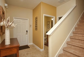 A hallway with a wooden desk, a white door, and a staircase. - Paradise Palms- 4 Bed Townhome W/splashpool-3202pp 4 Bedroom Townhouse by RedAwning (Kissimmee)
