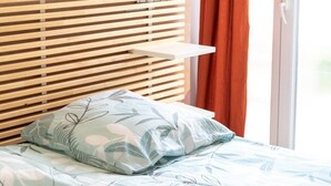 Een bed met een sierkussen met bloemenmotief en een houten latten hoofdgreep.