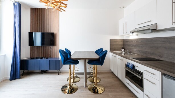 Een moderne keuken met een eethoek, een televisie en een bijzondere hanglamp.