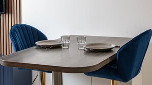Een eettafel met twee stoelen, een bord, een glas en bestek.