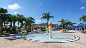 A pool area with a circular water feature, palm trees, and lounge chairs. - Paradise Palms- 5 Bed Townhome W/splashpool-3024 5 Bedroom Townhouse by RedAwning (Kissimmee)