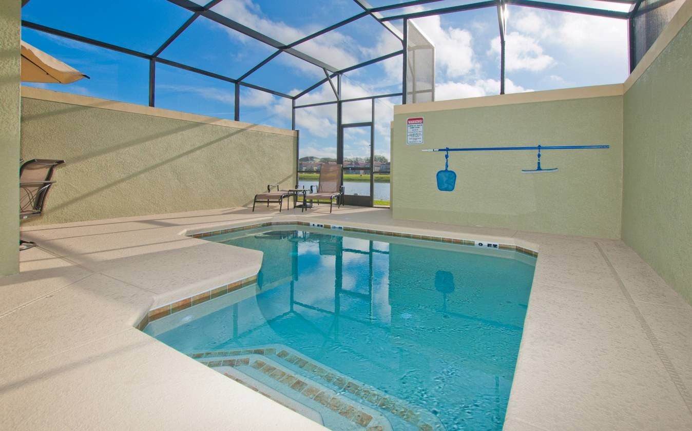 Una piscina interior con techo de cristal, una silla y un cartel de seguridad.
