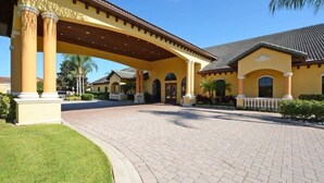 A hotel entrance with a covered walkway, palm trees, and a paved driveway. - Paradise Palms- 5 Bed Townhome W/splashpool-3024 5 Bedroom Townhouse by RedAwning (Kissimmee)