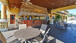 An outdoor bar area with a thatched roof, seating, and a poolside view. - Paradise Palms- 5 Bed Townhome W/splashpool-3024 5 Bedroom Townhouse by RedAwning (Kissimmee)