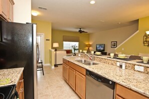 A kitchen with granite countertops, a dishwasher, and wooden cabinets. - Paradise Palms- 5 Bed Townhome W/splashpool-3024 5 Bedroom Townhouse by RedAwning (Kissimmee)