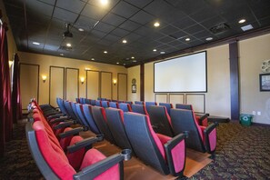 Ein Konferenzraum mit Reihen von Stühlen, einer Projektionsleinwand und einem Teppichboden.