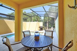 A covered outdoor patio with a round table and chairs, a grill, and a pool in the background. - Paradise Palms-4 Bed W/splashpool-3622pp 4 Bedroom Townhouse by RedAwning (Kissimmee)