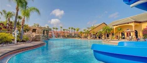 A pool area with a clear blue water feature, palm trees, and resort-style buildings.