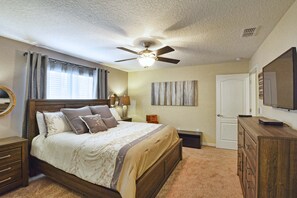 A bedroom with a bed, a ceiling fan, a nightstand, a dresser, a mirror, and a door. - Paradise Palms-4 Bed W/splashpool-3622pp 4 Bedroom Townhouse by RedAwning (Kissimmee)