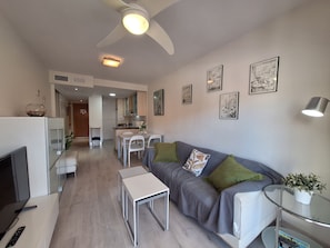 A modern living room with a sofa, a coffee table, a TV, and a dining area with chairs and a table. - FH - Holiday rental near the beach in Vera Playa (Vera playa)