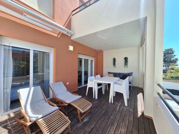 Un balcon avec des chaises en bois, une table et un canapé.