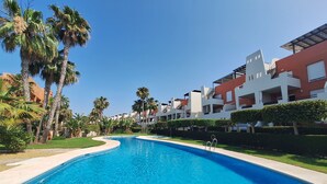 A swimming pool with clear blue water, surrounded by palm trees and modern buildings. - FH - Holiday rental near the beach in Vera Playa (Vera playa)