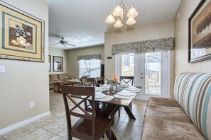 A dining area with a table set for four, a ceiling fan, and a sofa with a patterned cushion. - Paradise Palms- 4 Bed Townhome W/splashpool-3044pp 4 Bedroom Townhouse by RedAwning (Kissimmee)