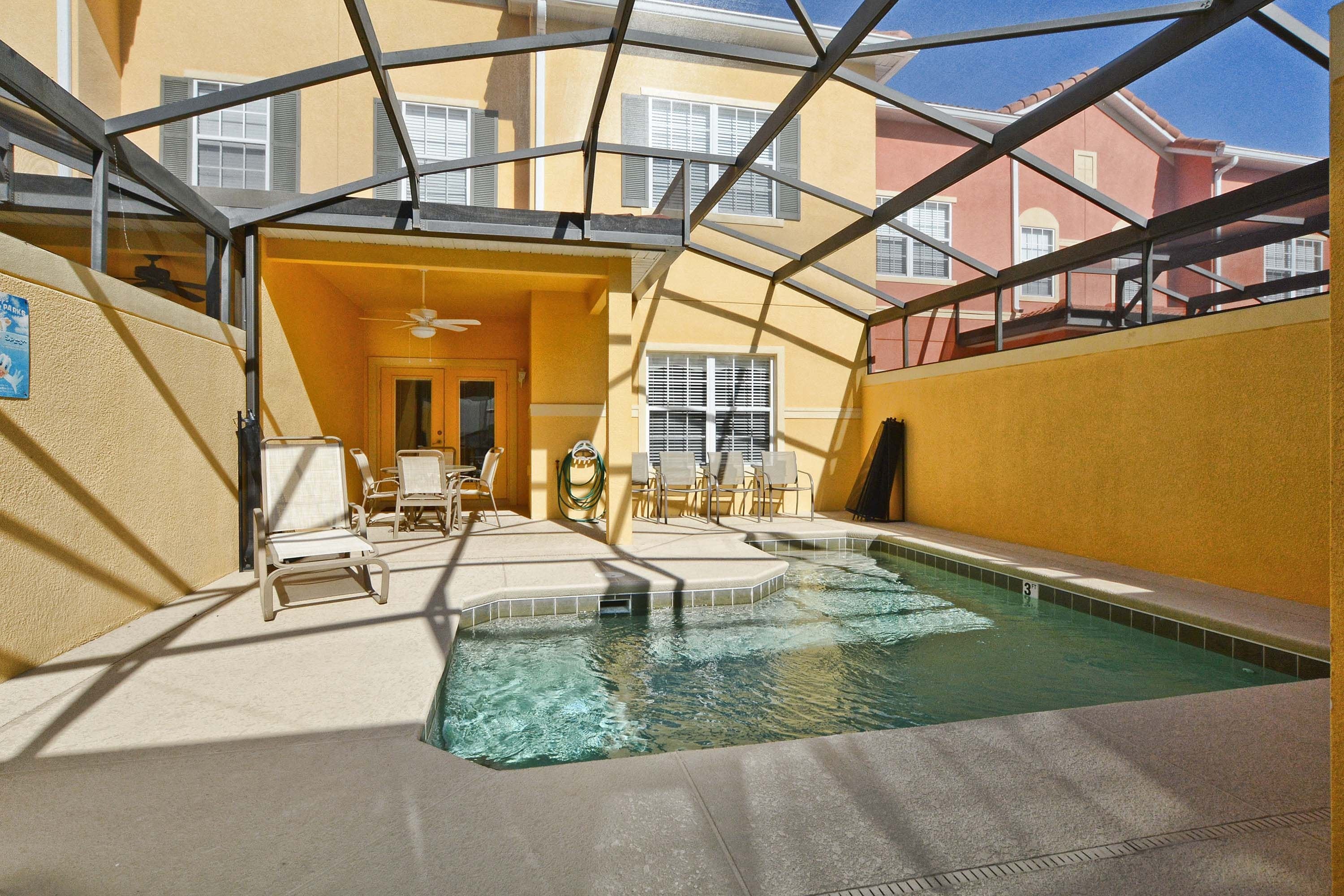 An indoor swimming pool with a glass ceiling, surrounded by lounge chairs and a sunbed.