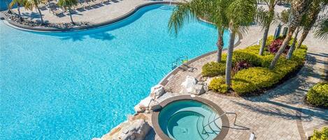 A large outdoor swimming pool with lounge chairs and palm trees.