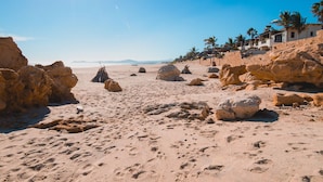 A desert beach with large rocks, palm trees, and a clear sky. - C301 Oceanview Penthouse with infinity pool and jacuzzi (San Jose del Cabo)