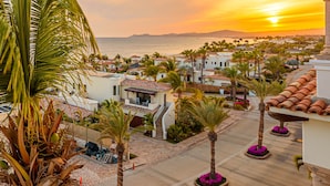 A coastal residential area with houses, palm trees, and a sunset view. - C301 Oceanview Penthouse with infinity pool and jacuzzi (San Jose del Cabo)