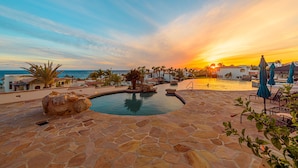 A stone pool with a sunset view, surrounded by palm trees and lounge chairs. - C301 Oceanview Penthouse with infinity pool and jacuzzi (San Jose del Cabo)