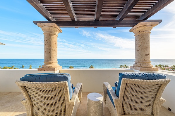 A balcony with wicker chairs and a view of the ocean.