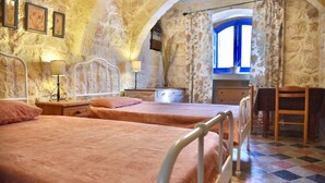 Une chambre avec deux lits, un bureau et une fenêtre ornée de rideaux à motifs floraux.