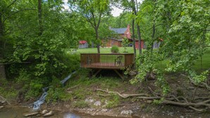A wooden deck with a view of a house and a small waterfall.