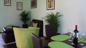 A room with a green sofa, a brown armchair, a dining table with four wine glasses and a bottle, and two potted plants. - La Casita Salesiana Aguascalientes (Aguascalientes)