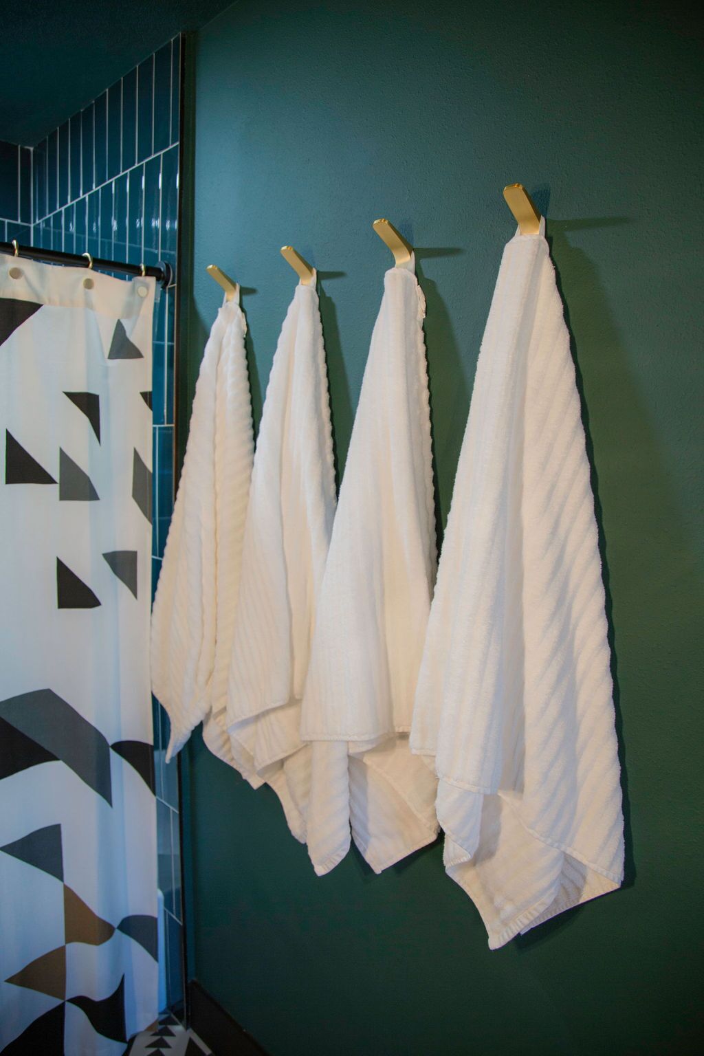Et badeværelse med en grøn væg og et bruseforhæng med geometrisk mønster.